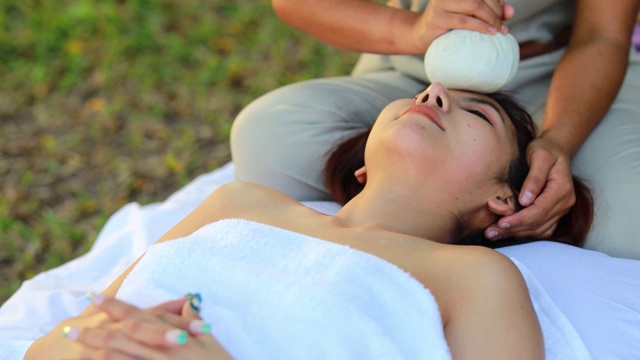 年轻的亚洲妇女接受头部按摩美容温泉在花园，水疗，健康，美容和放松的概念视频素材