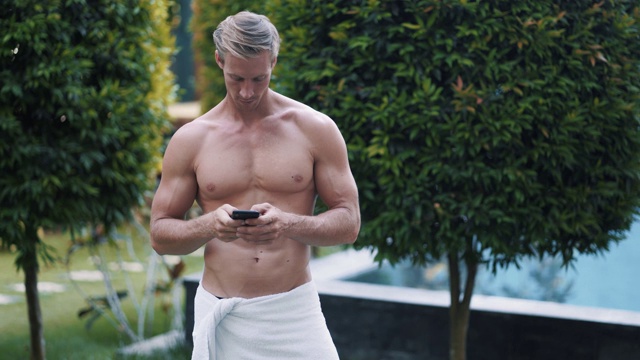 一个拿着毛巾的帅哥在游泳池边打电话视频下载