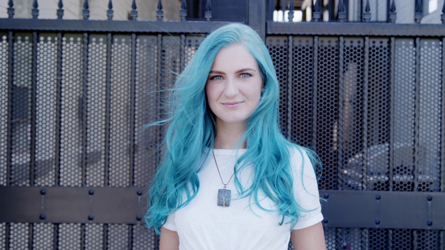 中心排列的慢动作拍摄美丽独特的活力时尚的年轻女人与有趣可爱的蓝绿色染头发站在户外摆姿势在夏天视频下载