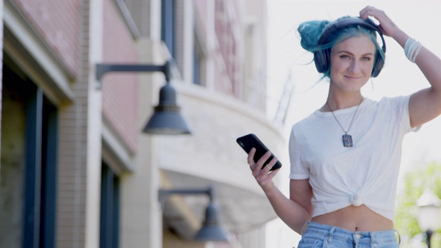 独特，活泼，时尚的年轻千禧女性在夏天户外听无线蓝牙耳机视频素材