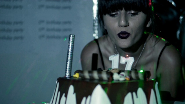 快乐的女孩吹着17岁生日派对上的蜡烛视频素材