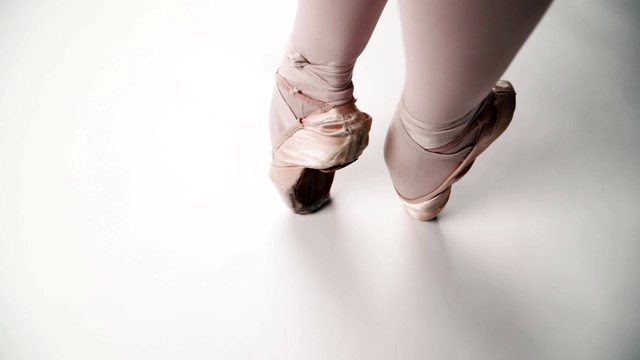 芭蕾舞腿上的白色背景特写。芭蕾舞女演员是优雅的足尖步法。缓慢的运动。俯视图视频素材