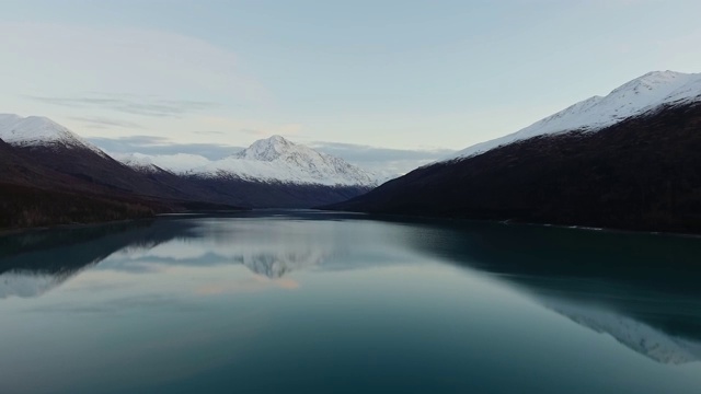 Аerial在白雪皑皑的山峰上翻来倒去的镜子湖上的镜头(埃克鲁特纳湖，阿拉斯加，美国)视频素材