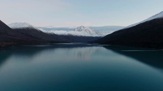 航空相机从山上移开，地平线上有云，山脚有一个镜子湖(埃克鲁特纳湖，阿拉斯加，美国)视频素材