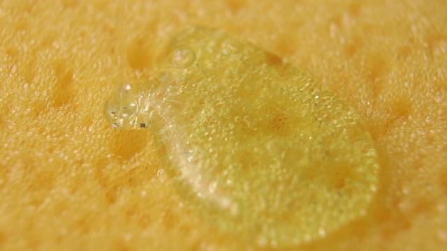 一个绿色的洗洁精液体凝胶在黄色多孔海绵上的特写视频素材