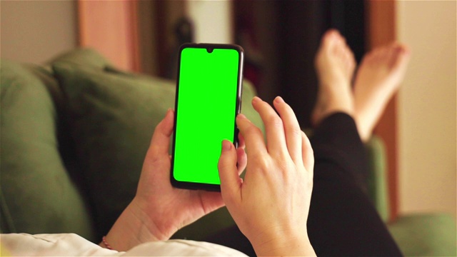 后视图的深褐色持有色度键绿色屏幕智能手机观看内容视频下载