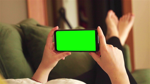 后视图的深褐色持有色度键绿色屏幕智能手机观看内容视频下载