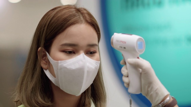 耐心的亚洲妇女用体温计测量脸部和手部的温度视频下载