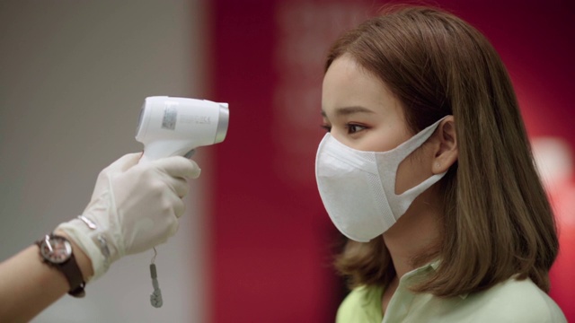 耐心的亚洲妇女用体温计测量脸部和手部的温度视频素材