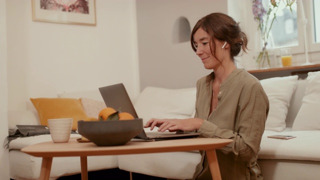 坐在客厅地板上用笔记本电脑打字的女人视频素材