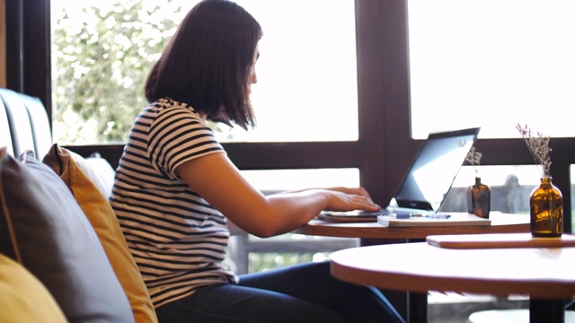 一个在咖啡馆用笔记本电脑工作的女人视频素材