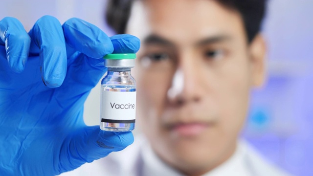 领导亚洲男性科学家微笑着，手拿安瓿在科学实验室的病毒研究冠状病毒或Covid-19疫苗。在生命科学实验室工作的卫生保健研究人员。科学和技术。视频素材
