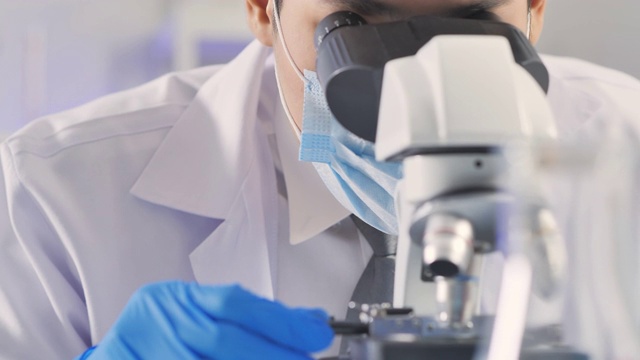 领导亚洲男性科学家观察显微镜焦点从病毒到实验室技术研究到冠状病毒或Covid-19。在生命科学实验室工作的卫生保健研究人员。科学技术，科学实验室视频素材
