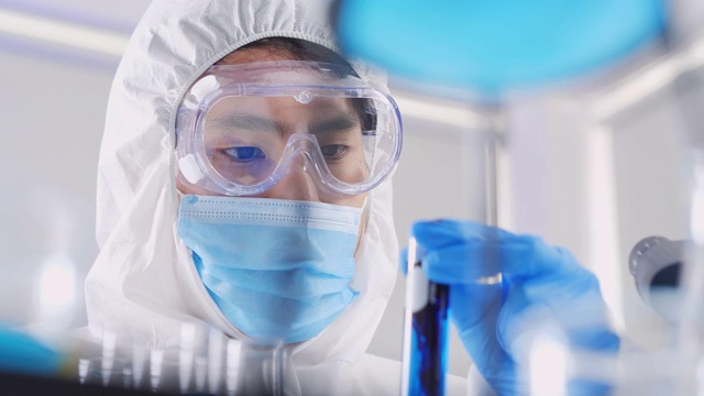 近距离观察亚洲科学家在实验室混合试管进行测试，在实验室对研究冠状病毒或Covid-19的玻璃器皿上进行含有化学液体的实验。科学技术，医学概念视频素材