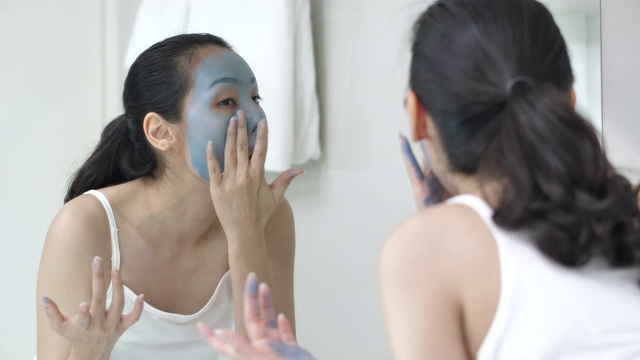 快乐的年轻女子在浴室里敷面膜-美容产品视频素材