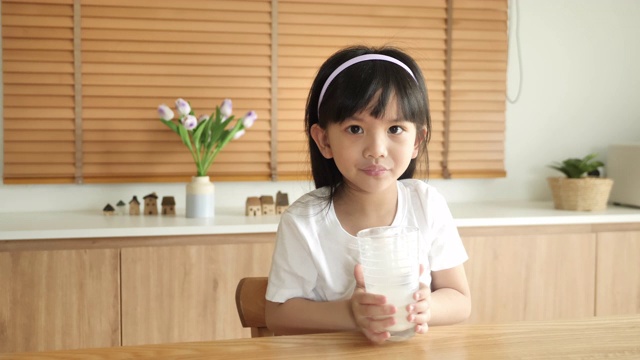 小女孩在家里喝牛奶。视频下载