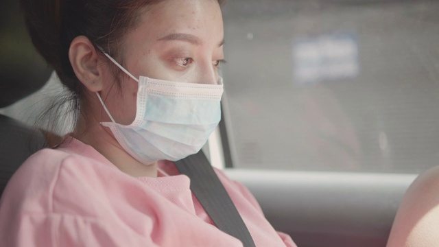 特写:一名亚洲妇女戴着面具坐在车里。视频素材