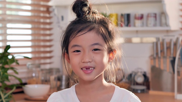 肖像自信的亚洲儿童女孩微笑，显示没有牙齿在看相机摆姿势在家里与快乐的情绪享受成功的生活方式。家庭工作室视频下载