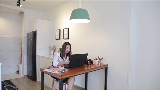 亚洲华人妇女使用笔记本电脑在家里工作视频素材