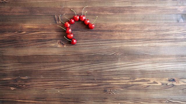 Сherry浆果组成的心符号和单词爱在一张木桌上。视频下载