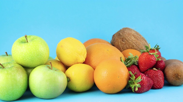 新鲜的苹果，柠檬，橙子，草莓，猕猴桃和椰子在蓝色的背景视频素材