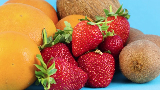 近距离接触新鲜的有机草莓，橙子和猕猴桃在蓝色的背景视频素材