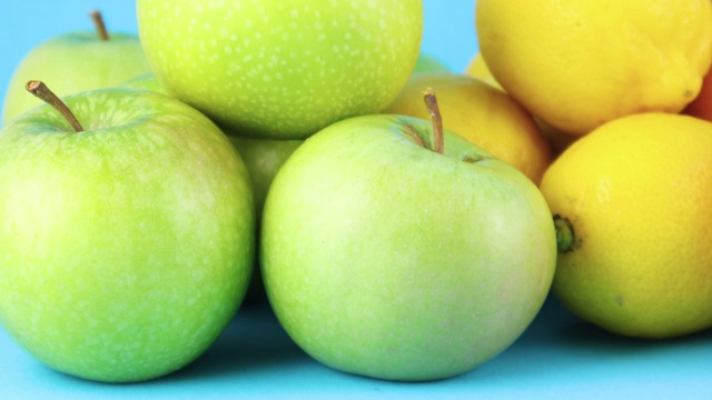 近距离观察新鲜的有机绿色苹果和柠檬在蓝色的背景视频素材