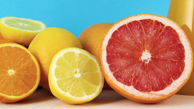 靠近切片柚子，柠檬和橙色在蓝色的背景视频素材