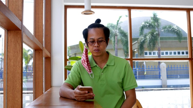(中):一群亚洲男人在咖啡店里戴着面具。视频下载