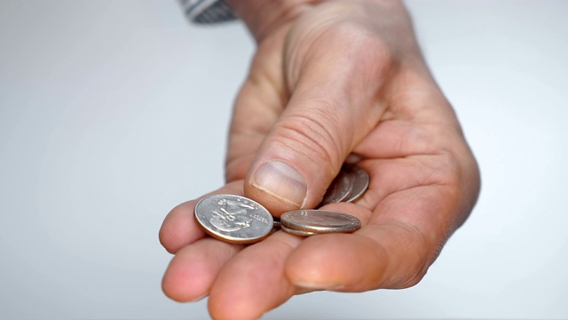 一个男人慢慢地检查着手里的一件小东西，试图找到一枚合适的硬币视频素材