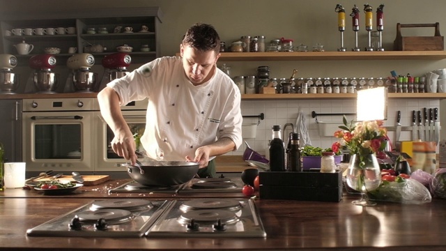 穿着餐厅制服的厨师正在用夹子搅拌意大利面。煮意大利面视频素材