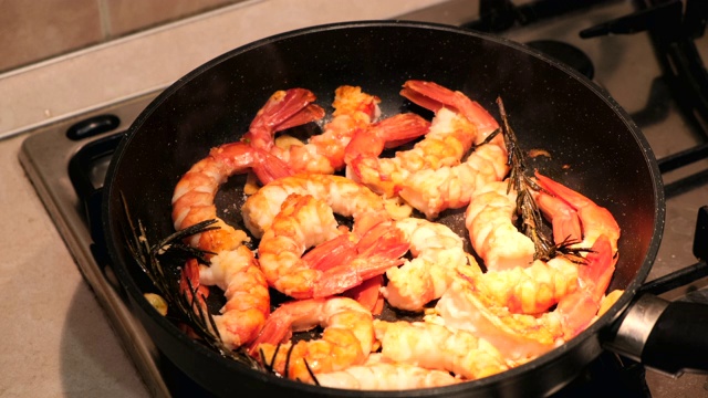生虾在平底锅里烤在黑色背景。新鲜海鲜食材-虾尾即可烹煮，无需腌料。虾在锅里视频素材