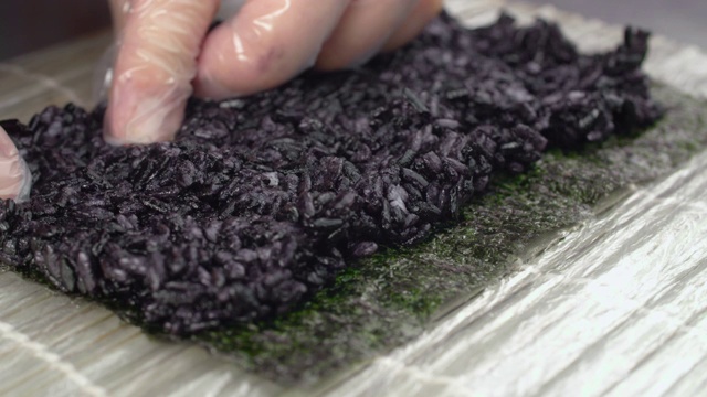 厨师将黑米放在海苔上，用慢动作制作寿司卷视频下载