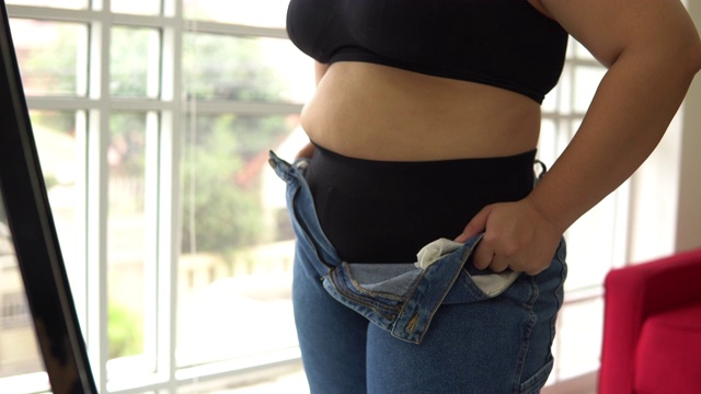体重超标的女性试图穿牛仔裤视频素材