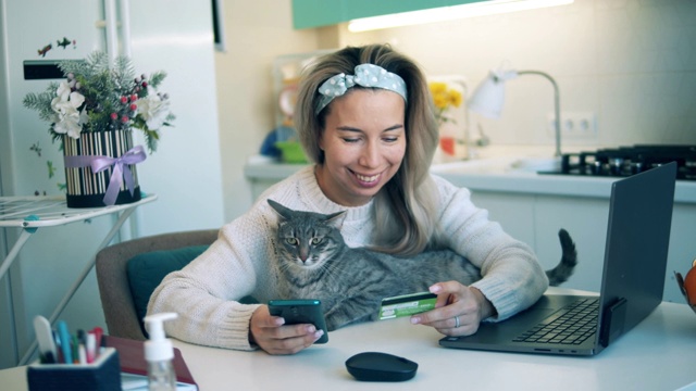 带着一只猫的微笑女人正在网上购物视频下载