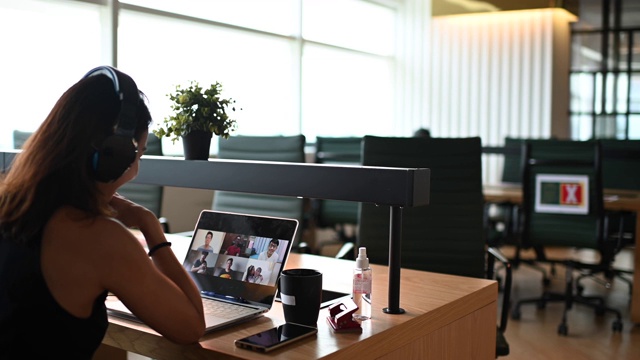一位留着长发的亚洲华人女士正在联合办公室与她的商业伙伴进行视频电话会议视频素材