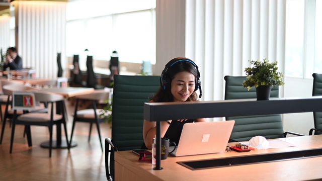 一位亚洲华裔美丽的女白领戴着口罩对着摄像机进行视频通话，与他的商业伙伴进行视频会议视频素材