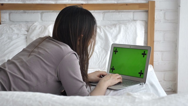 女人在床上用绿色屏幕的笔记本电脑视频素材