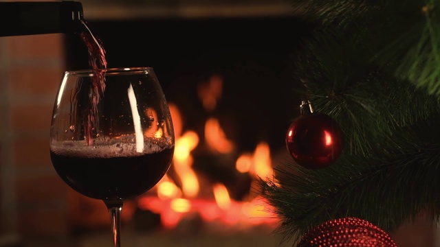 在燃烧的壁炉的背景下，葡萄酒倒进玻璃杯视频下载