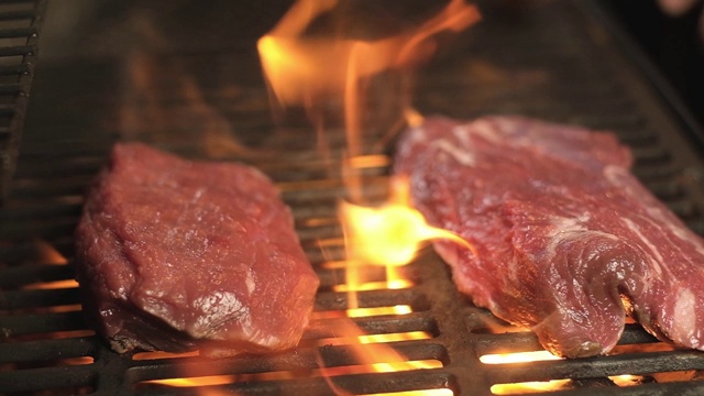 两块多汁的生肉在热烤架上用明火烤着。烧烤。视频下载