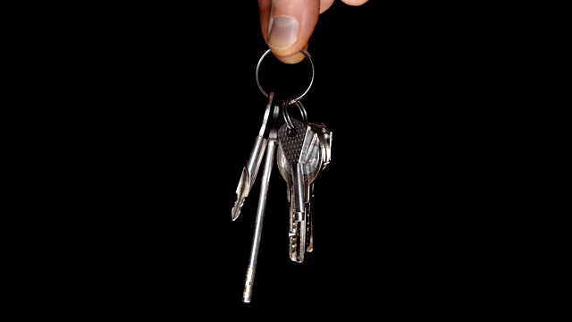 一串闪亮的镀铬公寓钥匙在一个男性的手在一个黑色的背景视频下载