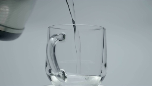 将开水从闪亮的金属茶壶中倒入玻璃杯中视频素材