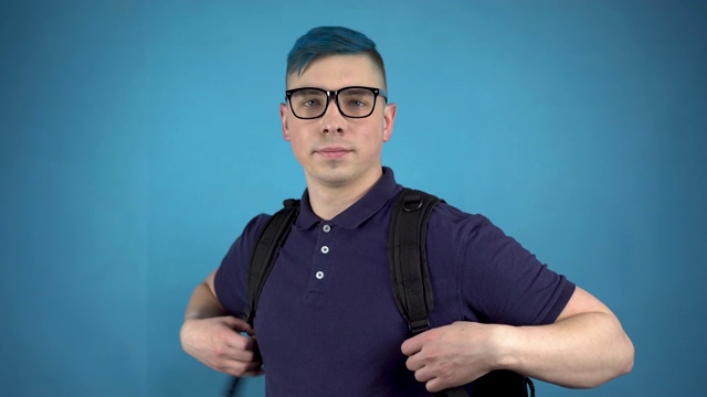 一个戴着眼镜、头发是蓝色的学生伸出大拇指。一个在蓝色背景下背着公文包的另类男人。视频素材