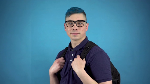 一个戴着眼镜、头发是蓝色的学生伸出大拇指。一个在蓝色背景下背着公文包的另类男人。视频素材