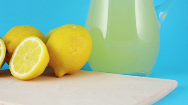 特写的新鲜柠檬水和切好的柠檬板上的蓝色背景视频下载