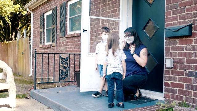 一位母亲和她的孩子在新冠肺炎大流行期间戴着防护口罩离家视频素材