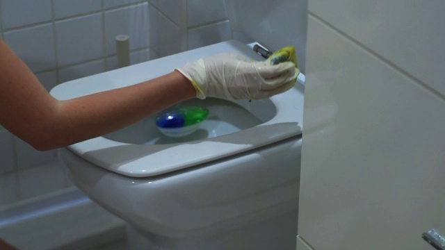 戴着白手套的年轻女子在洗马桶视频素材