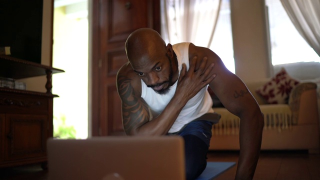 男人在笔记本电脑上看体育课，在家做运动视频下载