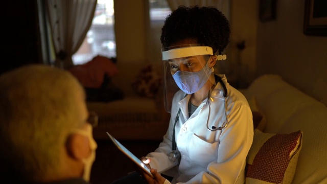 女医生拜访她的病人在他的家庭预约与数字平板电脑视频素材