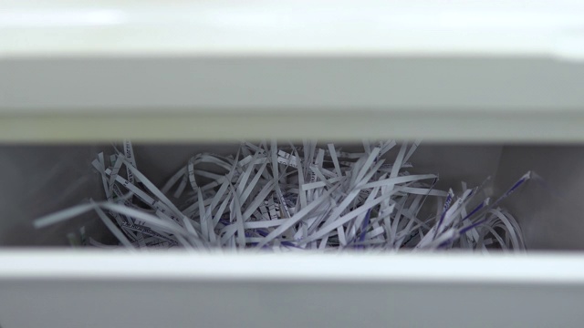 裁纸落入容器内。碎纸机破坏特写纸。碎纸机把纸切成条状。容器视图视频素材
